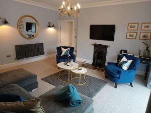 a living room with blue chairs and a fire place at The West Wing at Eriviat Hall Hot Tub in Henllan