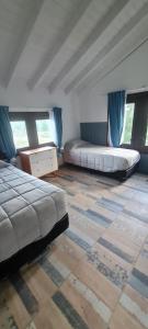 a room with two beds and a table and windows at Mountain House departamentos de montaña in Villa Meliquina