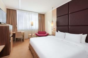 a hotel room with a large bed and a red chair at Radisson Blu Szczecin in Szczecin