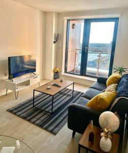 ein Wohnzimmer mit einem Sofa und einem TV in der Unterkunft Amazing 1 bedroom flat with balcony views to the city 19th floor in Manchester