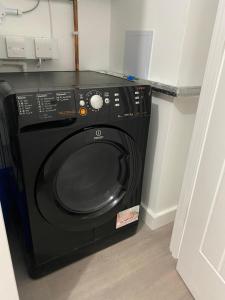 a black washing machine in a corner of a room at Escape Homes in Barking