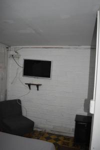 a living room with a tv on a white brick wall at Esmed Hostel in Medellín