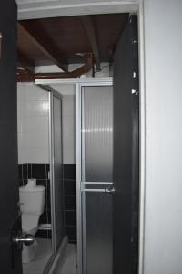 baño con aseo y puerta de ducha de cristal en Esmed Hostel, en Medellín