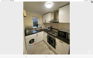 a kitchen with white cabinets and a sink and a microwave at One bed flat in Southampton