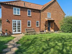 ein Backsteinhaus mit Rasen davor in der Unterkunft Brisley North Norfolk cosy cottage garden pub and walks in Beetley