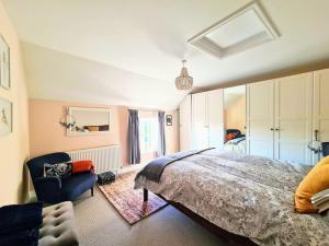 ein Schlafzimmer mit einem großen Bett und einem Stuhl in der Unterkunft Brisley North Norfolk cosy cottage garden pub and walks in Beetley