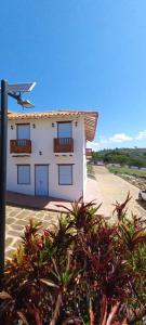 a white building with windows and plants in front of it at Acogedora Casa en Barichara in Barichara