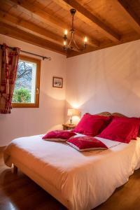 a bedroom with a large bed with red pillows at GITE BALNEO LES AMARYLLIS in Taninges