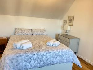 1 dormitorio con 1 cama con toallas en Braunton Breaks - Ambrose Cottage, en Braunton
