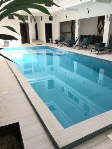 a large swimming pool with blue water in a building at Résidence Marie France MENDY in Toubab Dialaw