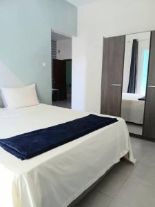 Un dormitorio con una cama blanca con una manta azul. en Résidence Marie France MENDY en Toubab Dialaw