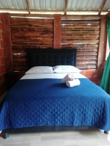 Un dormitorio con una cama azul con una toalla. en Cabañas orquídea, en Norcasia