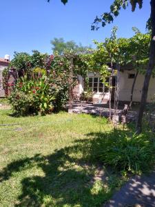 a yard with a house with a tree and flowers at Casa céntrica El Rosal (cabaña) in San Rafael