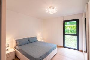 a white bedroom with a bed and a window at 7 - Gioiello Moderno a Montagnola in Collina d'Oro