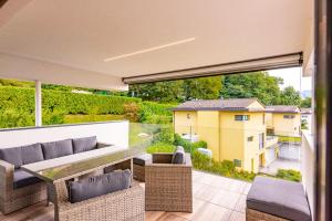a patio with a couch and chairs on a balcony at 7 - Gioiello Moderno a Montagnola in Collina d'Oro