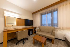 um quarto de hotel com uma secretária, uma cama e uma cadeira em JR CLEMENT INN HIMEJI em Himeji