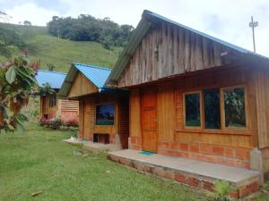 una cabaña de madera con una colina verde en el fondo en Cabañas orquídea, en Norcasia