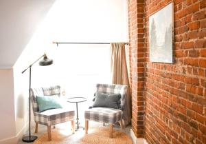 salon z 2 krzesłami i ceglaną ścianą w obiekcie The BARN - Washington Park, Private Guesthouse w mieście Denver