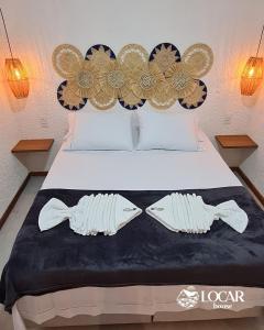 Un dormitorio con una cama con dos zapatos. en Apartamento luxo mais completo com 2 suítes Patacho - Milagres - AL, en Porto de Pedras