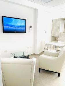 un salon avec des meubles blancs et une télévision à écran plat dans l'établissement Apart Center Madryn, à Puerto Madryn