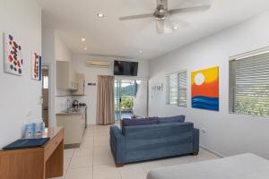 a living room with a blue couch and a kitchen at Waterview Airlie Beach in Airlie Beach