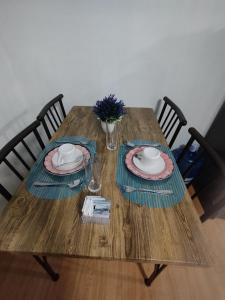 uma mesa de madeira com dois pratos e um vaso de flores em Staycation 2 Bedroom in Urban Deca Home Marilao em Marilao