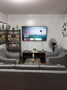 uma sala de estar com sofás e uma televisão de ecrã plano em Staycation 2 Bedroom in Urban Deca Home Marilao em Marilao
