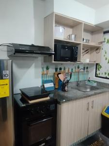 uma cozinha com um fogão e um lavatório em Staycation 2 Bedroom in Urban Deca Home Marilao em Marilao