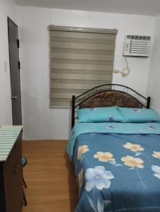 um quarto com uma cama com um edredão azul em Staycation 2 Bedroom in Urban Deca Home Marilao em Marilao