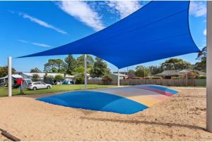 a blue umbrella sitting on top of a pile of sand at Discovery Parks - Burrill Lake, Ulladulla in Burrill Lake