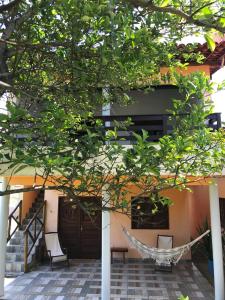 a hammock in front of a house with a tree at CHALÉ CAPOEIRA DOS MILAGRES in São Miguel dos Milagres