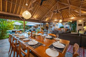 a dining room with a long wooden table and chairs at Villa Damai Manis in Seminyak