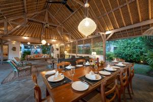 a dining room with a large wooden table and chairs at Villa Damai Manis in Seminyak
