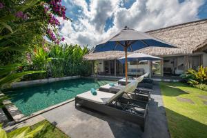 a swimming pool with two chairs and an umbrella at Villa Damai Manis in Seminyak