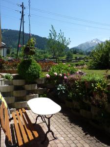 einen weißen Tisch und eine Bank in einem Garten mit Blumen in der Unterkunft Chalet Aebnetbode in Gstaad