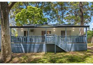 a house with a porch and a tree at Discovery Parks - Burrill Lake, Ulladulla in Burrill Lake