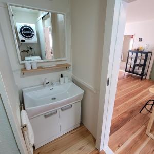 La salle de bains est pourvue d'un lavabo blanc et d'un miroir. dans l'établissement Biei Urban Villa, à Biei