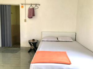 a bedroom with a white bed with an orange blanket at Tunas Rinjani Inn in Masbagik