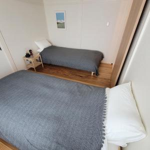 a small bedroom with two beds and a chair at Biei Central Villa - Green Garden in Biei