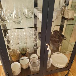 a glass cabinet with plates and wine glasses at Biei Urban Villa in Biei