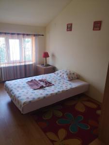 a bedroom with a bed with a flowered bedspread and a rug at Apartman Stanimirović in Zaječar