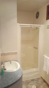 a white bathroom with a shower and a sink at Alexandra Parklife Deluxe Studio 2 in Alexandra