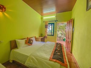 una camera da letto con un letto con pareti verdi e una finestra di Tuan Nam Homestay a Ninh Binh