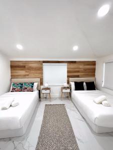 two white beds in a room with wooden walls at NEW Comfy and Modern House near Miami Airport in Miami