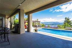 a patio with a pool and a view of the water at Stunning Lake View with Private Hot Tub, Pool snl, Outdoor Kitchen in West Kelowna