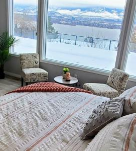 a bedroom with a bed and two chairs and a large window at Stunning Lake View with Private Hot Tub, Pool snl, Outdoor Kitchen in West Kelowna