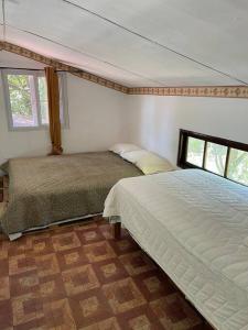 a bedroom with two beds and two windows at Eucalyptus Cabin Boquete in Bajo Boquete