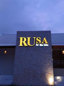 a sign on the side of a building with the rusga logo at Rusa by The Lake in Baturiti