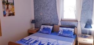um quarto com uma cama com lençóis azuis e uma janela em Villa Mali Ston (3588) em Mali Ston