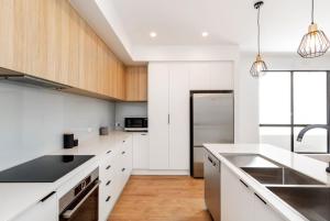 a kitchen with white countertops and wooden cabinets at Luxury private ensuite room close to Airport,City, Genelg Beach in Plympton